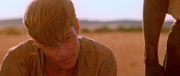 Movie still from “Gallipoli” (1981), directed by Peter Weir – A person in a field looking at the camera; Close Up shot, Over the shoulder angle