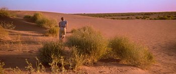 Movie still from “Gallipoli” (1981), directed by Peter Weir – A man walking through the desert with a surfboard; Extreme Wide shot, High angle