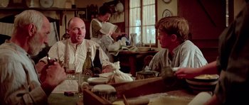 Movie still from “Gallipoli” (1981), directed by Peter Weir – Two men and a woman are sitting at a table; Medium shot, Over the shoulder angle