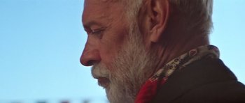 Movie still from “Gallipoli” (1981), directed by Peter Weir – An older man with a beard and a red tie; Close Up shot, Low angle