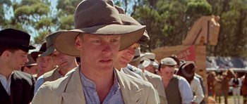 Movie still from “Gallipoli” (1981), directed by Peter Weir – A group of people in a field wearing hats; Close Up shot, Over the shoulder angle