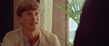 Movie still from “Gallipoli” (1981), directed by Peter Weir – A man sitting in front of a window with a potted plant; Close Up shot, Over the shoulder angle