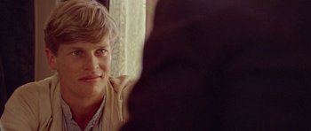 Movie still from “Gallipoli” (1981), directed by Peter Weir – A young man sitting in front of a window looking at the camera; Close Up shot, Over the shoulder angle