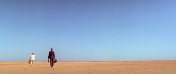 Movie still from “Gallipoli” (1981), directed by Peter Weir – A man and a woman walking across a beach; Extreme Wide shot, Over the shoulder angle