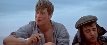 Movie still from “Gallipoli” (1981), directed by Peter Weir – A man sitting on the ground with a cigarette in his mouth; Close Up shot, Low angle