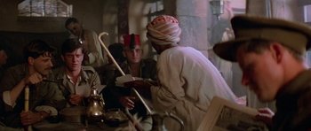 Movie still from “Gallipoli” (1981), directed by Peter Weir – A man sitting at a table with a man in a turban; Medium shot, Over the shoulder angle