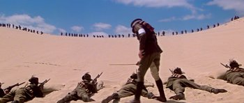 Movie still from “Gallipoli” (1981), directed by Peter Weir – A group of men in the sand with guns; Extreme Wide shot, Low angle