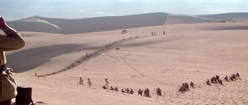Movie still from “Gallipoli” (1981), directed by Peter Weir – A group of people in the sand on a beach; Extreme Wide shot, High angle