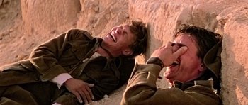 Movie still from “Gallipoli” (1981), directed by Peter Weir – Two men are laying on the ground and laughing; Close Up shot, Over the shoulder angle
