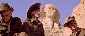 Movie still from “Gallipoli” (1981), directed by Peter Weir – A man wearing a hat standing in front of a statue; Close Up shot, Low angle