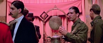 Movie still from “Gallipoli” (1981), directed by Peter Weir – A man standing in front of an antique gong; Medium shot, Over the shoulder angle