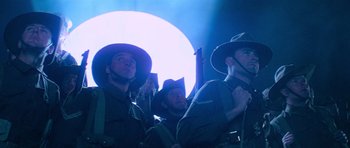 Movie still from “Gallipoli” (1981), directed by Peter Weir – A group of men standing next to each other in front of a light; Medium shot, Low angle