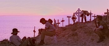 Movie still from “Gallipoli” (1981), directed by Peter Weir – A man sitting on a bench on the beach; Wide shot, Low angle