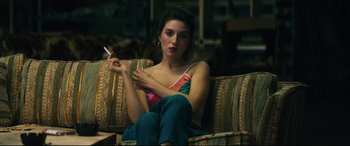 Movie still from “Galveston” (2018), directed by Mélanie Laurent – A woman sitting on top of a couch holding a cigarette; Medium shot, Over the shoulder angle
