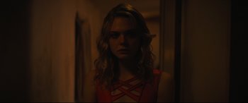 Movie still from “Galveston” (2018), directed by Mélanie Laurent – A woman with long blonde curly hair wearing a red top; Close Up shot, Over the shoulder angle