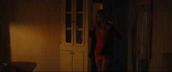 Movie still from “Galveston” (2018), directed by Mélanie Laurent – A woman in a red dress standing next to a white cabinet; Medium shot, Over the shoulder angle