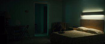 Movie still from “Galveston” (2018), directed by Mélanie Laurent – A man sitting on a couch in a dark room; Wide shot, High angle