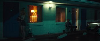 Movie still from “Galveston” (2018), directed by Mélanie Laurent – A man sitting on a chair in front of two windows; Wide shot, Over the shoulder angle