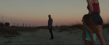 Movie still from “Galveston” (2018), directed by Mélanie Laurent – A man standing on top of a sandy beach at dusk; Wide shot, Low angle