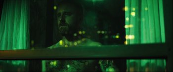 Movie still from “Galveston” (2018), directed by Mélanie Laurent – A man with a beard is looking out of a car window at night; Medium shot, Low angle