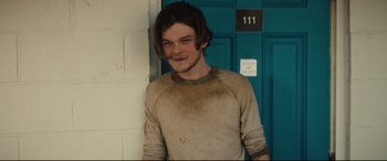 Movie still from “Galveston” (2018), directed by Mélanie Laurent – A young man standing in front of a blue door; Medium shot, Over the shoulder angle