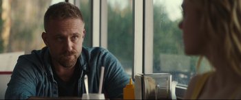 Movie still from “Galveston” (2018), directed by Mélanie Laurent – A person sitting at a table in front of a window; Close Up shot, Over the shoulder angle