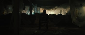 Movie still from “Galveston” (2018), directed by Mélanie Laurent – A man sitting on a chair in a dark room; Wide shot, Low angle