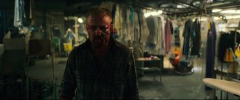 Movie still from “Galveston” (2018), directed by Mélanie Laurent – A man with a bloody face in a room full of clothes; Medium shot, Low angle