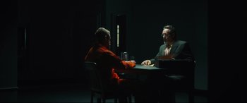 Movie still from “Galveston” (2018), directed by Mélanie Laurent – Two men sitting at a table in a dark room; Wide shot, Over the shoulder angle