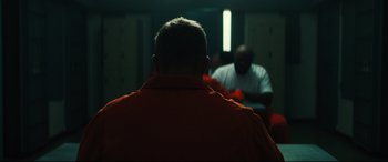 Movie still from “Galveston” (2018), directed by Mélanie Laurent – A man in orange is sitting in front of another man in orange; Medium shot, Over the shoulder angle