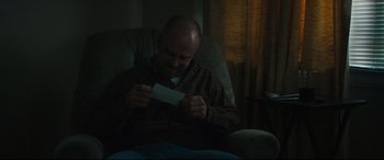 Movie still from “Galveston” (2018), directed by Mélanie Laurent – A man sitting in a chair looking at a piece of paper; Medium shot, Over the shoulder angle