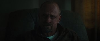 Movie still from “Galveston” (2018), directed by Mélanie Laurent – A man with a beard is sitting on a couch; Close Up shot, Over the shoulder angle