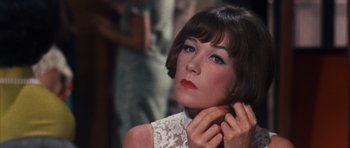 Movie still from “Gambit” (1966), directed by Ronald Neame – A person wearing a white dress; Close Up shot, Over the shoulder angle