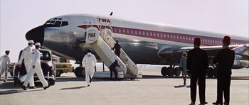 Movie still from “Gambit” (1966), directed by Ronald Neame – Three people are boarding a twa airplane; Extreme Wide shot, Low angle