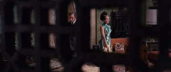 Movie still from “Gambit” (1966), directed by Ronald Neame – A man and a woman standing next to each other; Wide shot, High angle