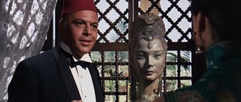 Movie still from “Gambit” (1966), directed by Ronald Neame – A man standing next to a statue of a woman's face; Close Up shot, Over the shoulder angle