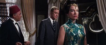 Movie still from “Gambit” (1966), directed by Ronald Neame – A man and a woman standing next to each other in a room; Medium shot, Low angle