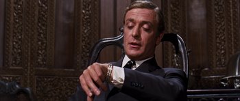 Movie still from “Gambit” (1966), directed by Ronald Neame – A man sitting in a chair looking at his watch; Close Up shot, Low angle