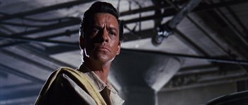 Movie still from “Gambit” (1966), directed by Ronald Neame – A person wearing a suit and tie; Close Up shot, Low angle