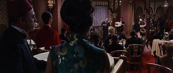 Movie still from “Gambit” (1966), directed by Ronald Neame – A group of people sitting in a room; Wide shot, Over the shoulder angle