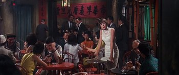 Movie still from “Gambit” (1966), directed by Ronald Neame – A group of people sitting at tables in a restaurant; Wide shot, High angle