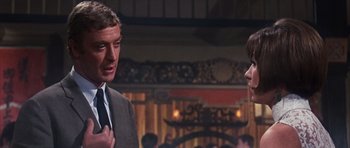 Movie still from “Gambit” (1966), directed by Ronald Neame – A man in a suit and tie talking to another man; Close Up shot, Over the shoulder angle