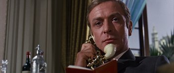 Movie still from “Gambit” (1966), directed by Ronald Neame – A man in a suit holding a phone to his ear; Close Up shot, Low angle