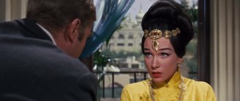 Movie still from “Gambit” (1966), directed by Ronald Neame – A man and a woman in a yellow dress; Close Up shot, Over the shoulder angle