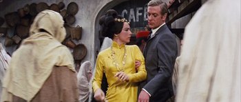 Movie still from “Gambit” (1966), directed by Ronald Neame – A man and a woman dressed up in a yellow dress; Medium shot, Over the shoulder angle