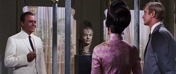 Movie still from “Gambit” (1966), directed by Ronald Neame – A woman standing in front of a mirror looking at a statue; Close Up shot, Over the shoulder angle