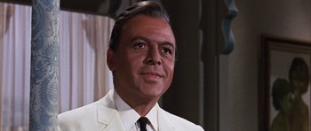 Movie still from “Gambit” (1966), directed by Ronald Neame – A man in a white suit and black tie; Close Up shot, Low angle
