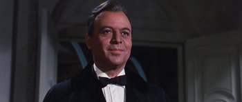 Movie still from “Gambit” (1966), directed by Ronald Neame – An older man in a black suit and bow tie; Close Up shot, Low angle