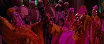 Movie still from “Gambit” (1966), directed by Ronald Neame – A group of men and women dressed up in costumes; Medium shot, Over the shoulder angle