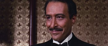 Movie still from “Gambit” (1966), directed by Ronald Neame – A person wearing a suit and tie; Close Up shot, High angle